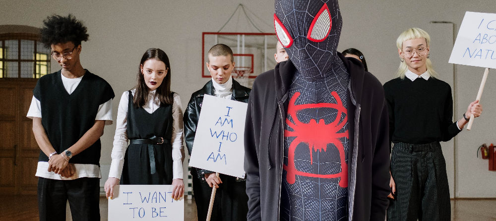 Young man in a superhero costume with teenage activists.